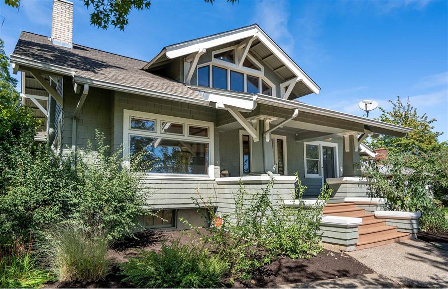 Craftsman-style home with a green facade, broad porch, and lush garden in College Hill Neighborhood of Eugene Oregon