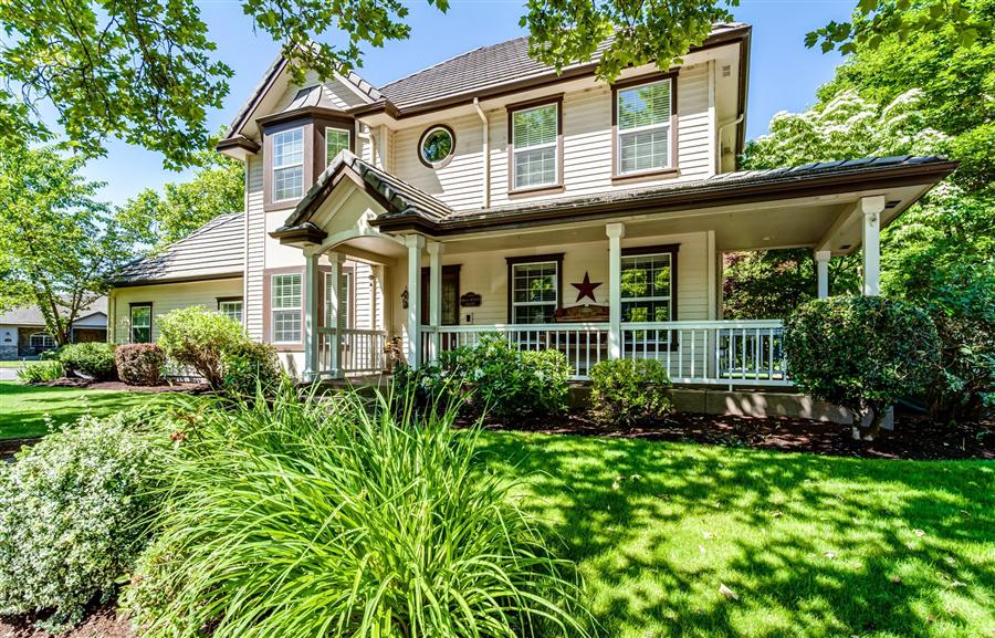 Colonial-style home with a covered porch and lush landscaping in Ferry Street Bridge Eugene Area